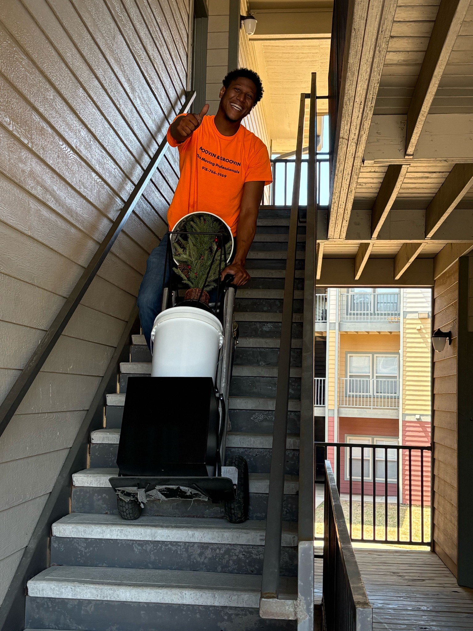 Moovin & Groovin mover using a hand truck on apartment stairs during a Glenpool to Okmulgee move.