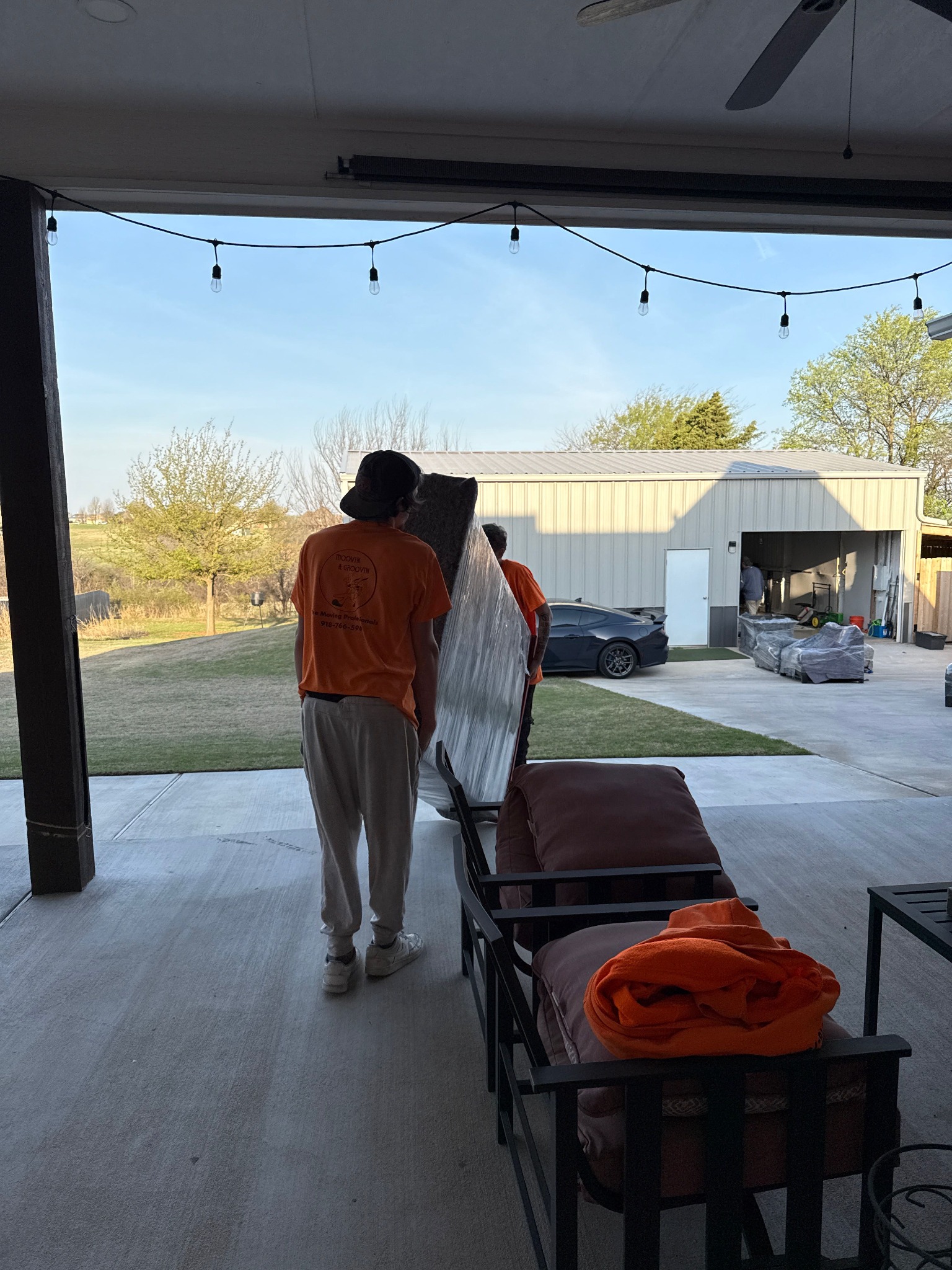 Two Moovin & Groovin movers carrying a large bookshelf during a full-service move from Tuttle to Norman.