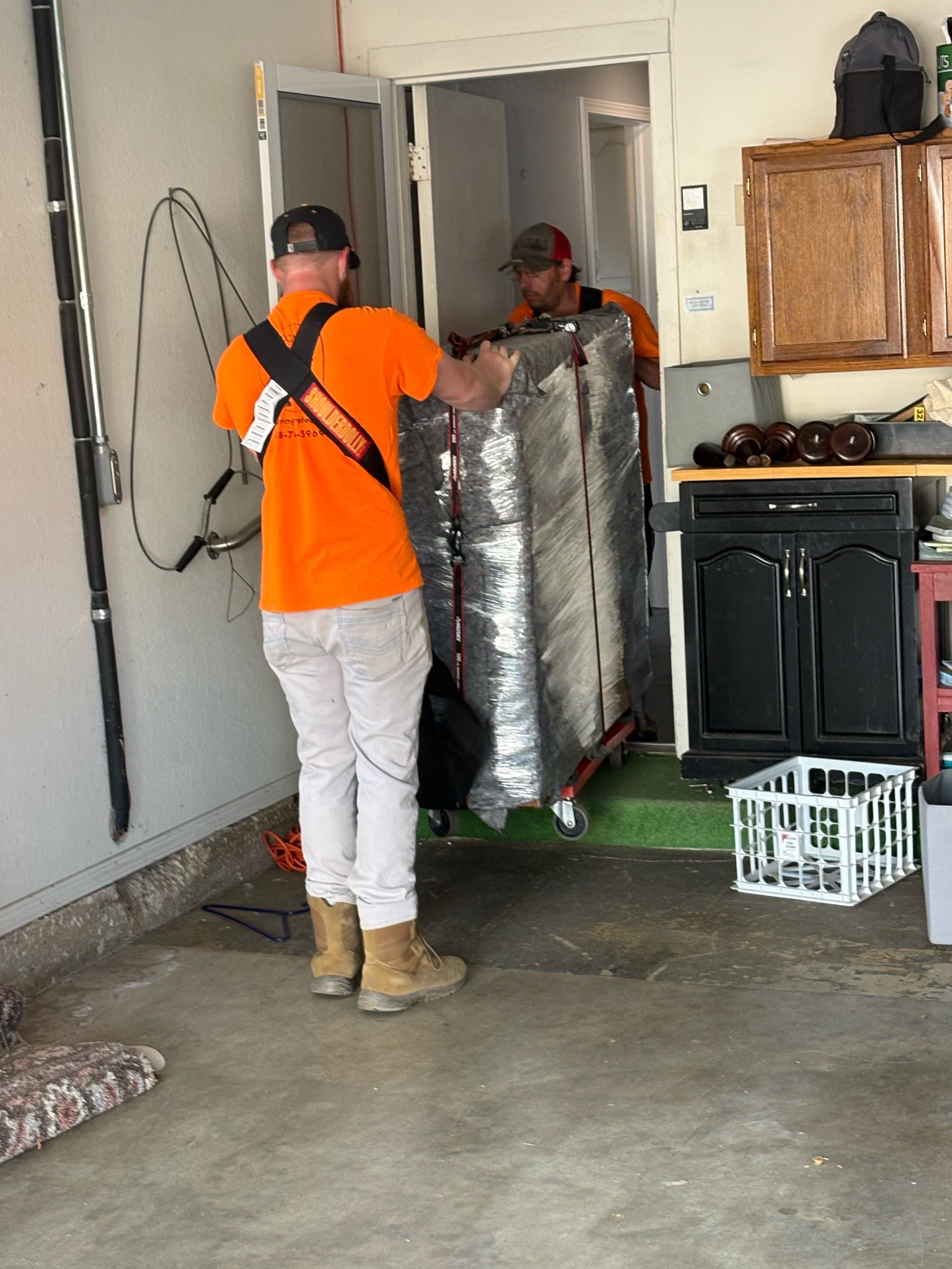 Two Moovin & Groovin movers handling a padded piano during a Tulsa to Morris move.