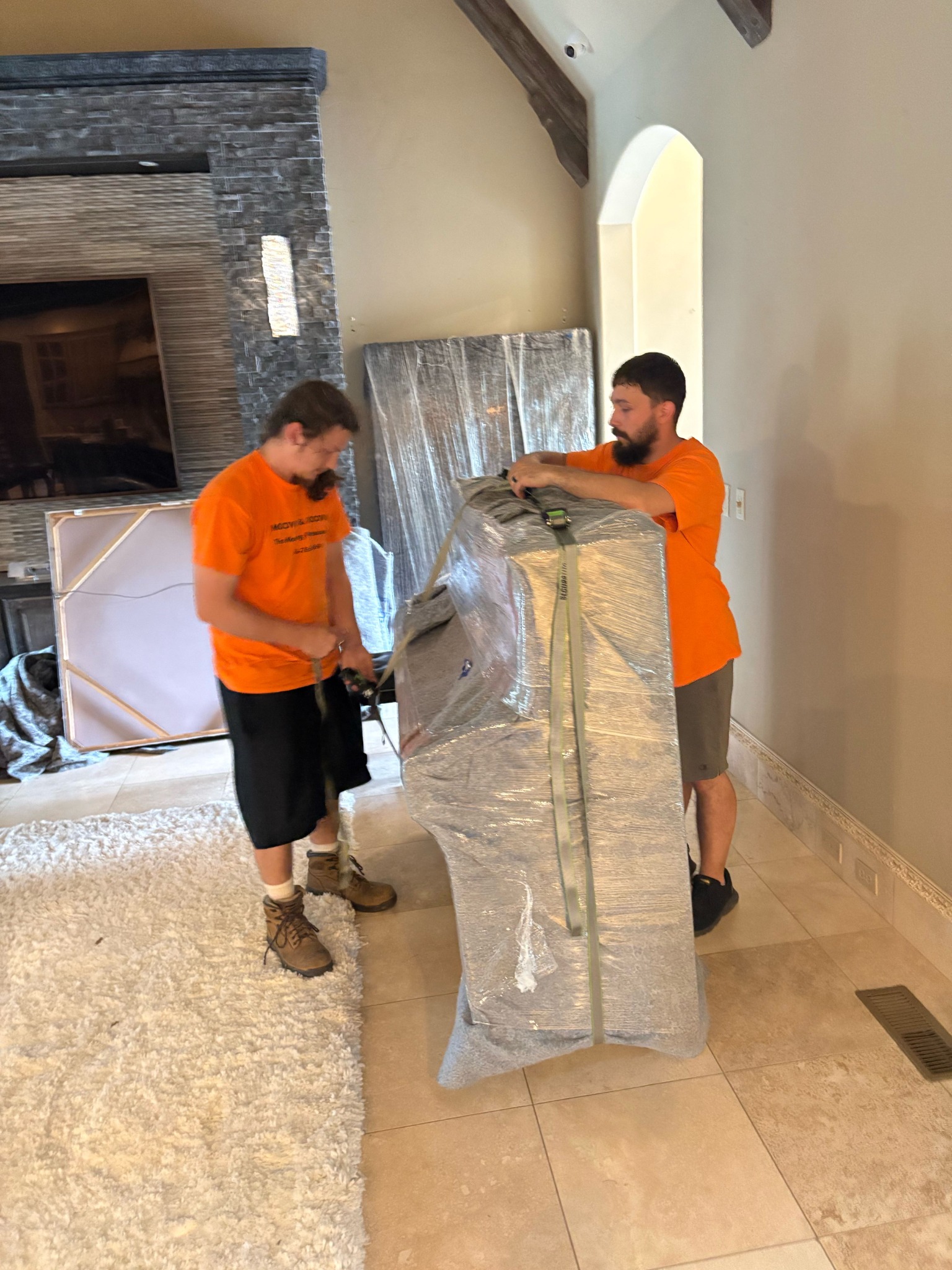 Moovin & Groovin movers padding and securing a piano during a full-service move from Jenks to Tulsa.