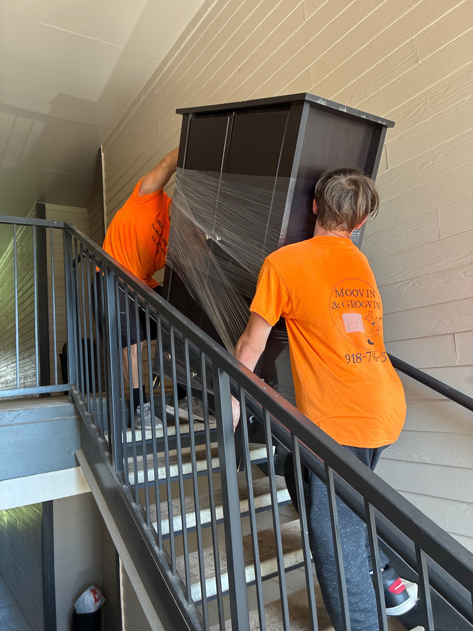Two Moovin & Groovin movers carrying a large book hutch up apartment stairs during a Kingfisher to Oklahoma City move.